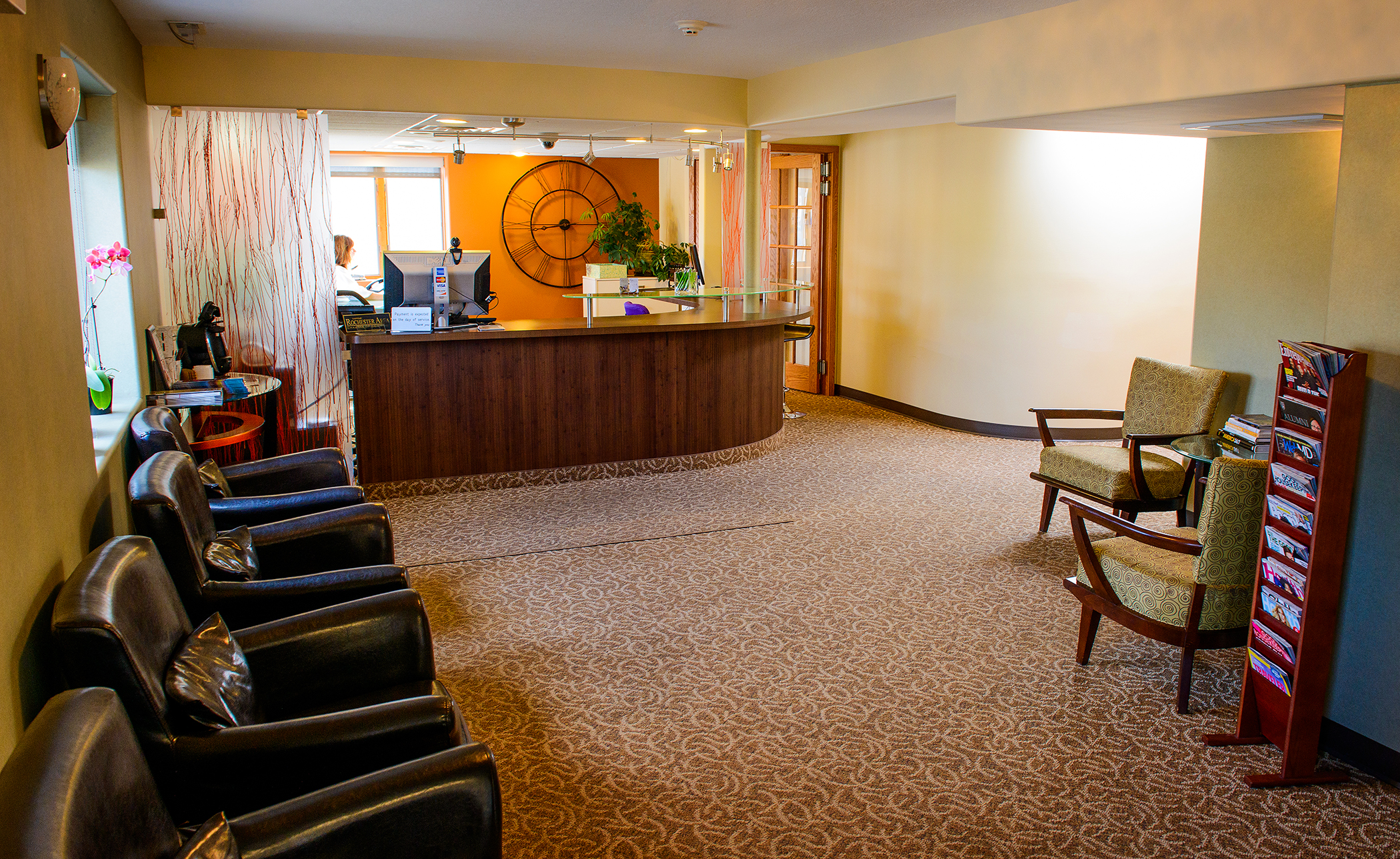 The image shows an interior space with a lobby area featuring a reception desk, chairs, a carpeted floor, and a decorative element on the wall.