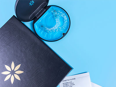 A black book with a blue flower on its cover sits next to a clear plastic mouthguard case containing a blue mouthguard.