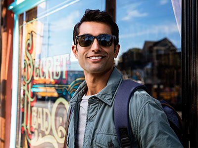 A man wearing sunglasses stands confidently against a window display with a sign that reads  Secret Garden  in the background.