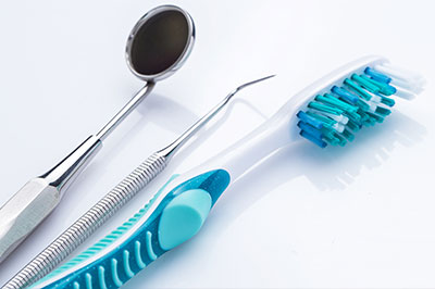 A set of dental tools including a toothbrush, dental mirror, and dental pick displayed on a white background.