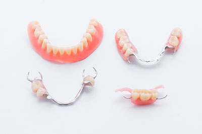 The image displays four pairs of dentures with teeth missing, arranged on a white background, showcasing their design and structure.