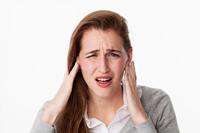 The image shows a woman with her hand on her head, appearing to be in pain or discomfort, with a concerned facial expression.